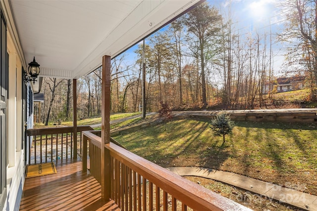 wooden deck featuring a porch and a lawn