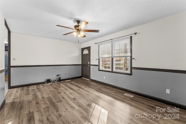 empty room featuring a textured ceiling, light wood-type flooring, and ceiling fan