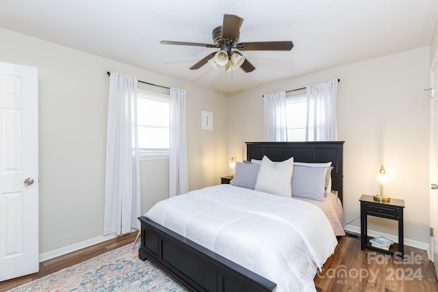 bedroom featuring multiple windows, ceiling fan, and dark hardwood / wood-style flooring