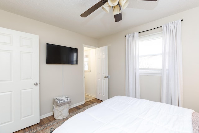 bedroom featuring ceiling fan, dark hardwood / wood-style flooring, and a textured ceiling