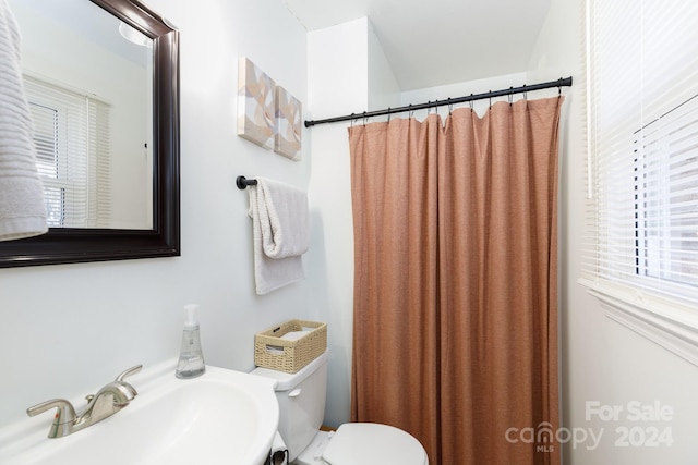 bathroom with a shower with shower curtain, toilet, and sink