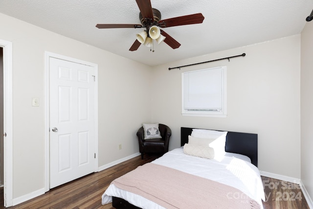 bedroom with ceiling fan, dark wood-type flooring, and a textured ceiling