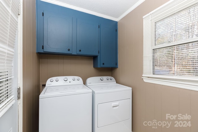 laundry room featuring cabinets, a textured ceiling, wooden walls, washer and clothes dryer, and ornamental molding