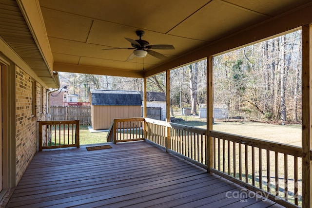 deck featuring a shed, ceiling fan, and a lawn