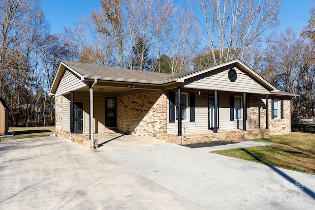 ranch-style house featuring a carport, covered porch, and a front lawn