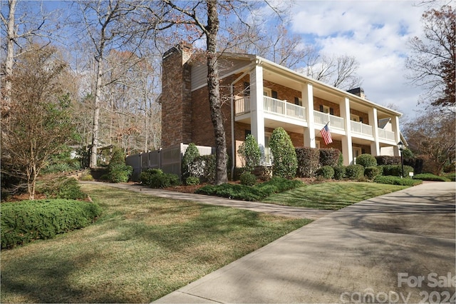 view of side of property featuring a lawn and a balcony