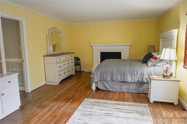 bedroom with crown molding, a fireplace, and light wood-type flooring