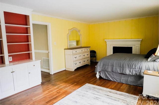 bedroom with ornamental molding and dark wood-type flooring