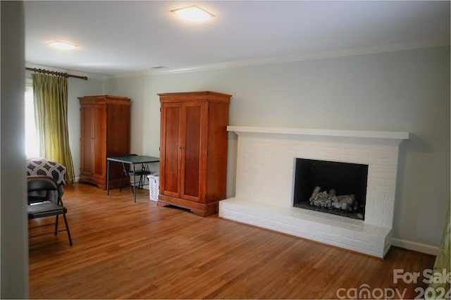 living room featuring hardwood / wood-style floors, crown molding, and a brick fireplace