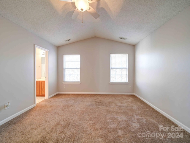 carpeted spare room featuring a textured ceiling, ceiling fan, and lofted ceiling