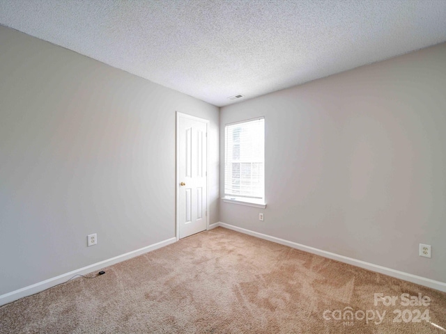 carpeted empty room featuring a textured ceiling