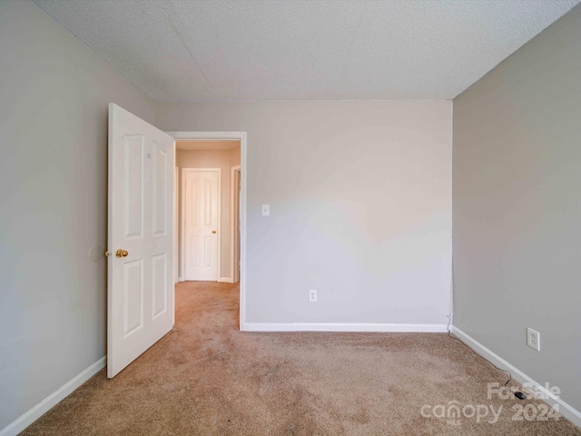 unfurnished room with light carpet and a textured ceiling