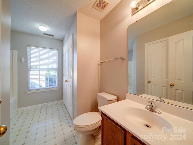 bathroom with a washtub, tile patterned floors, a textured ceiling, toilet, and vanity