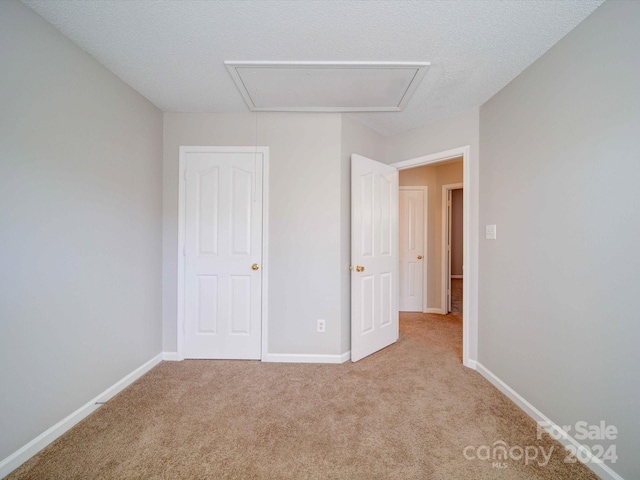 unfurnished bedroom with light carpet and a textured ceiling