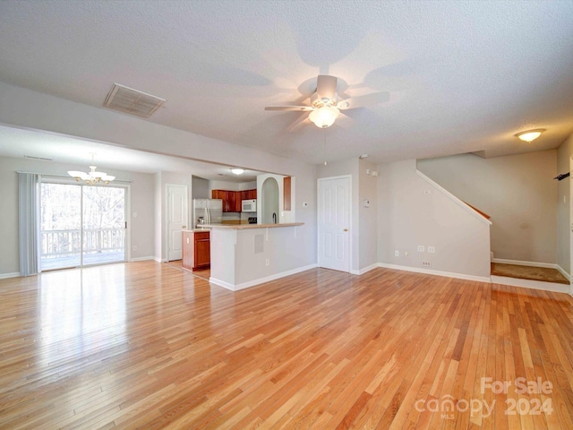 unfurnished living room with a textured ceiling, light hardwood / wood-style floors, and ceiling fan with notable chandelier