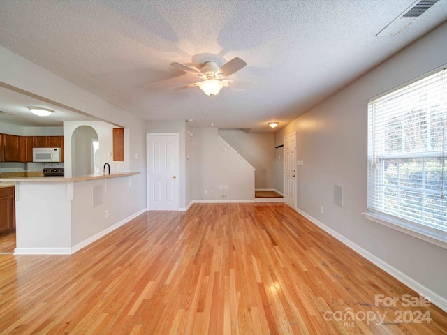 unfurnished living room featuring light hardwood / wood-style floors and a textured ceiling