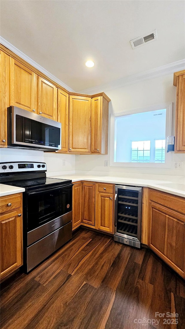 kitchen with appliances with stainless steel finishes, beverage cooler, dark hardwood / wood-style flooring, and sink