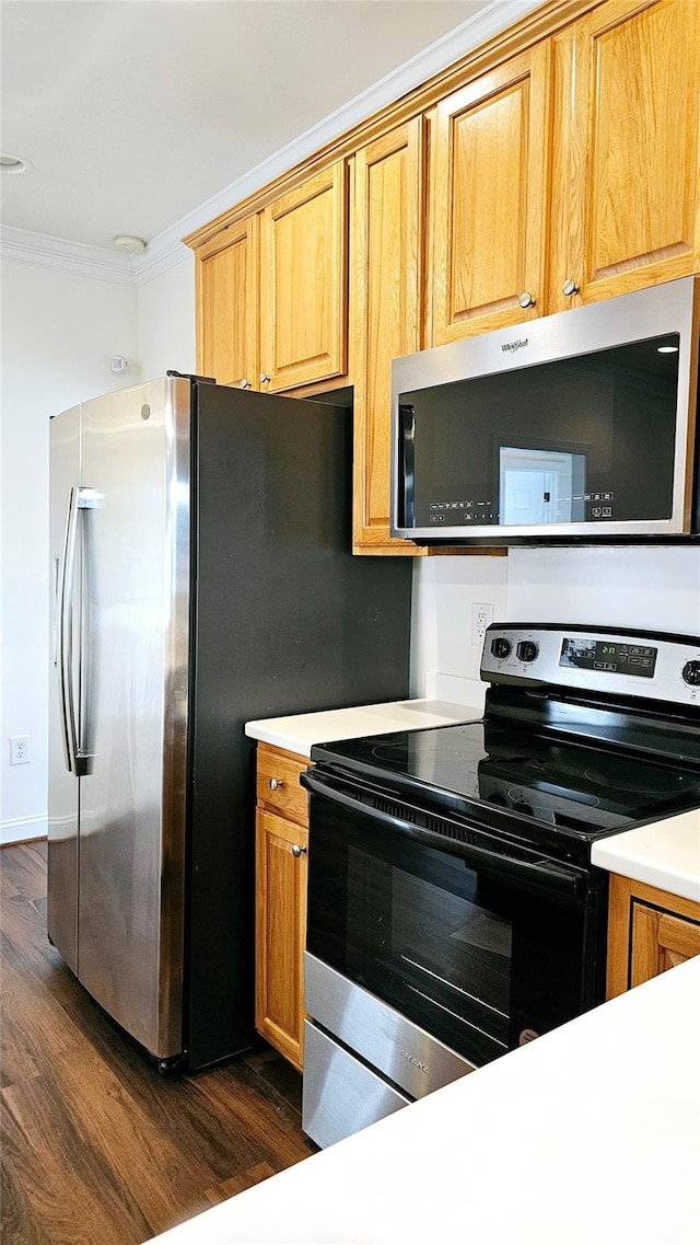 kitchen featuring dark wood-type flooring, stainless steel appliances, and ornamental molding