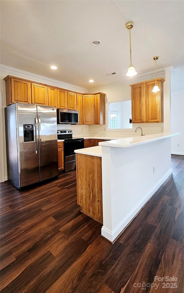 kitchen featuring dark wood-type flooring, hanging light fixtures, appliances with stainless steel finishes, and kitchen peninsula