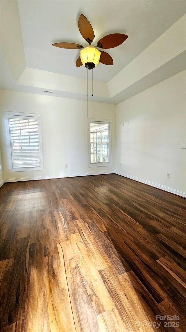 spare room featuring a healthy amount of sunlight, wood-type flooring, and a tray ceiling