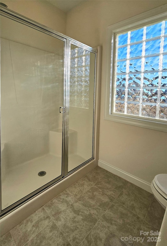 bathroom featuring toilet and a shower with door