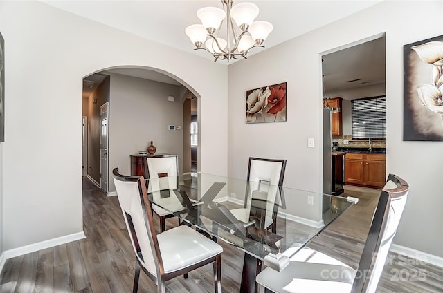 dining room featuring dark wood-type flooring, sink, and a notable chandelier