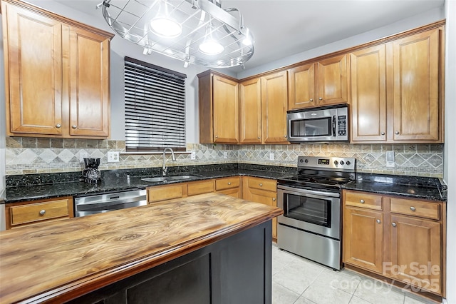 kitchen with wood counters, stainless steel appliances, sink, backsplash, and light tile patterned floors