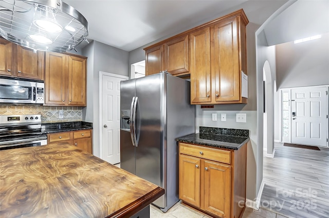 kitchen with decorative backsplash, dark stone counters, and stainless steel appliances