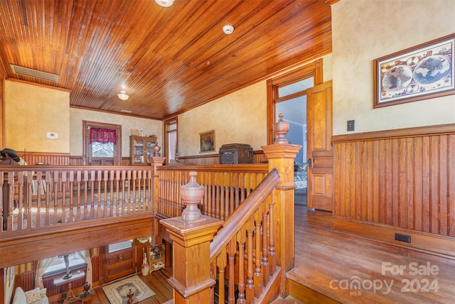 staircase featuring ornamental molding, hardwood / wood-style flooring, wood walls, and wood ceiling