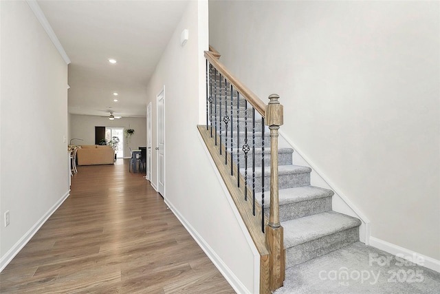 staircase with hardwood / wood-style floors and ceiling fan