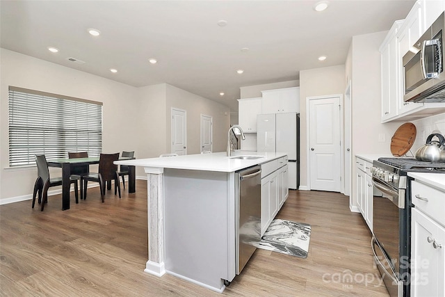 kitchen featuring appliances with stainless steel finishes, sink, an island with sink, and white cabinets