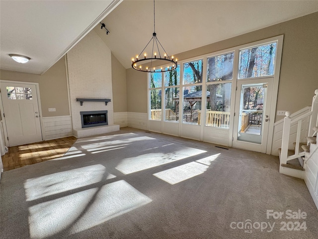 unfurnished living room featuring carpet flooring, a fireplace, high vaulted ceiling, and a chandelier