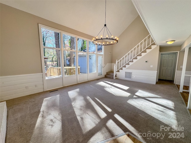 unfurnished dining area with carpet floors, a notable chandelier, and wood walls