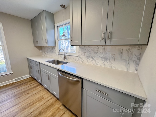 kitchen featuring a wealth of natural light, light hardwood / wood-style flooring, stainless steel dishwasher, and sink