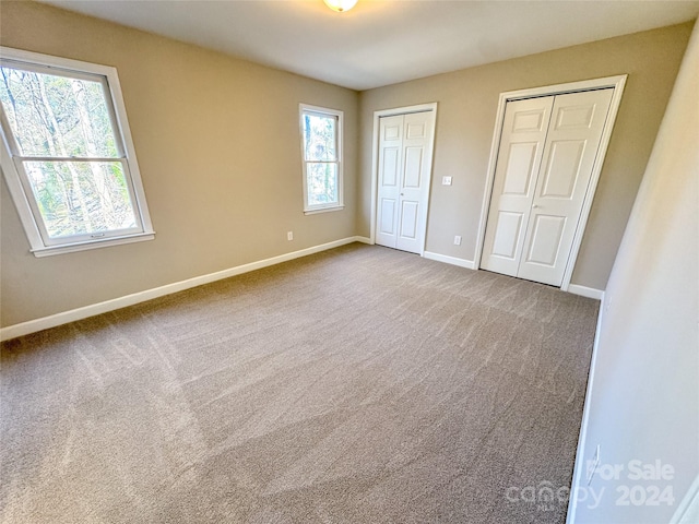 unfurnished bedroom featuring carpet flooring and multiple closets