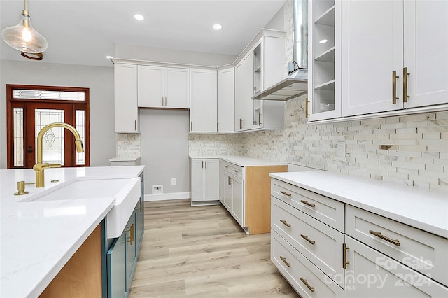 kitchen with light hardwood / wood-style floors, white cabinetry, and hanging light fixtures