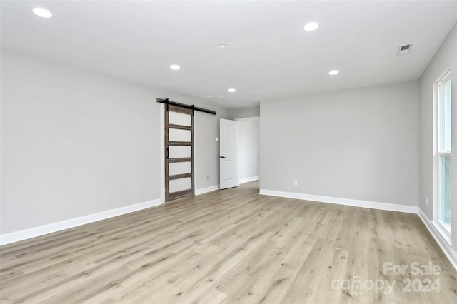 empty room with a barn door and light hardwood / wood-style floors