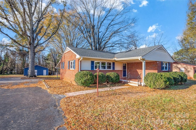 ranch-style home with covered porch, a garage, and an outdoor structure