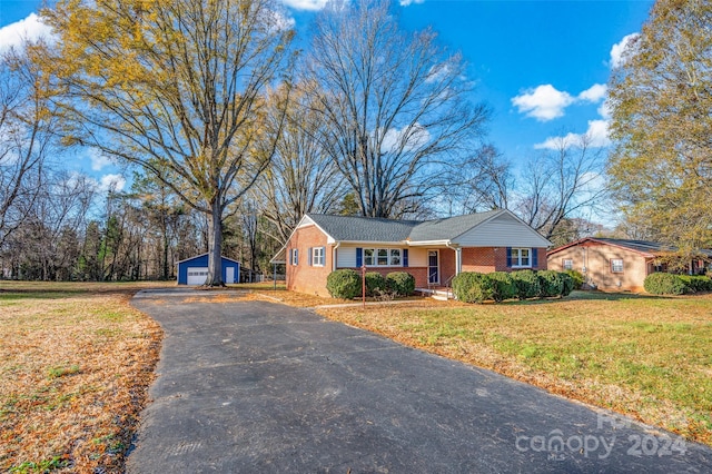 single story home with an outbuilding, a porch, a garage, and a front yard