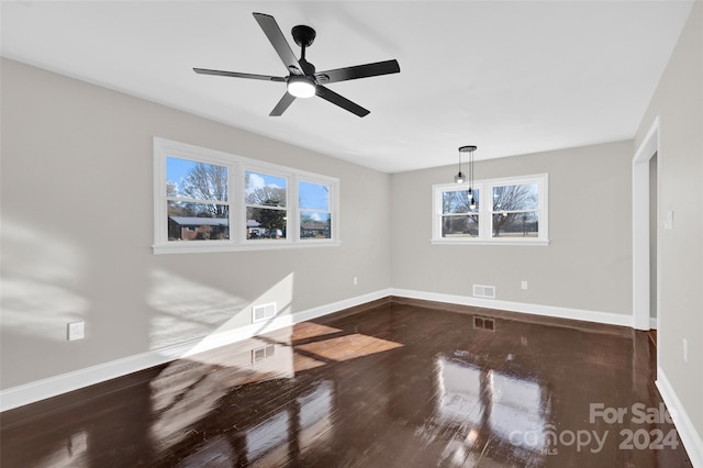 empty room featuring dark hardwood / wood-style flooring, a wealth of natural light, and ceiling fan