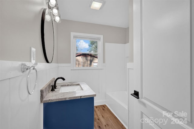 bathroom featuring hardwood / wood-style flooring, vanity, and shower / washtub combination