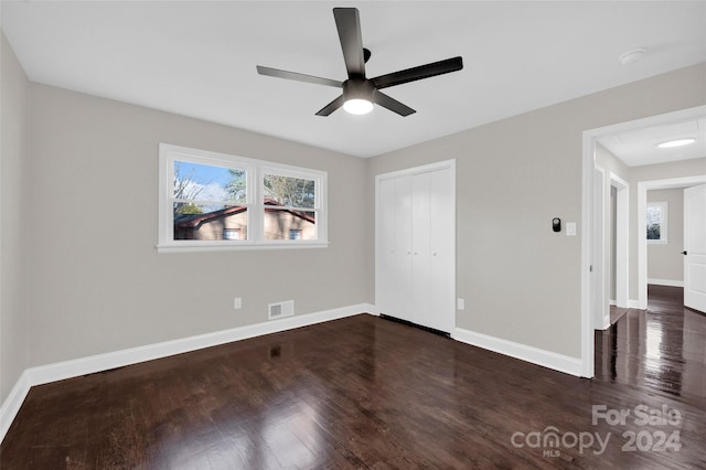 unfurnished bedroom featuring a closet, dark wood-type flooring, and ceiling fan