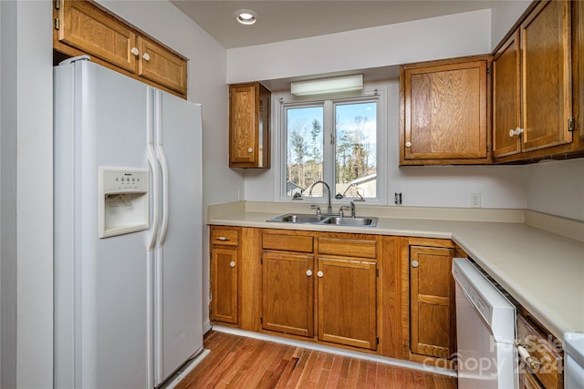 kitchen featuring white appliances, light hardwood / wood-style floors, and sink