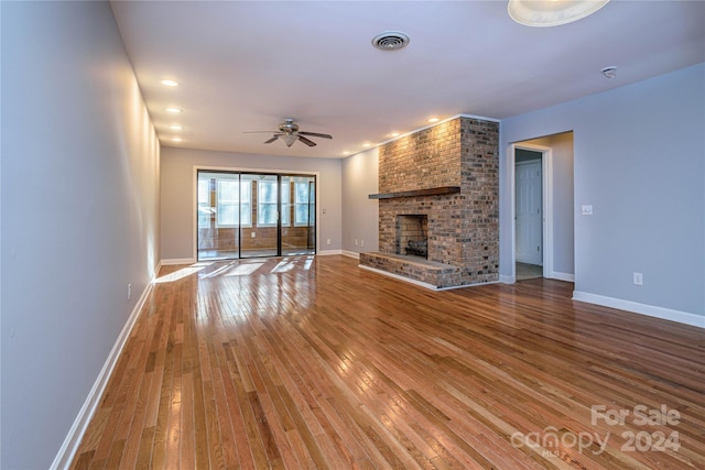 unfurnished living room with hardwood / wood-style floors, a brick fireplace, and ceiling fan