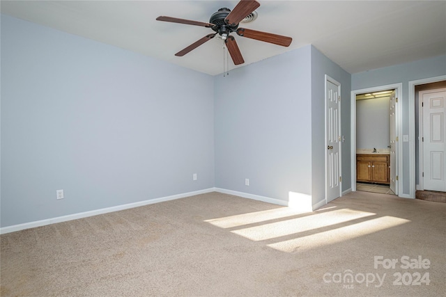 unfurnished bedroom featuring light carpet, a closet, ceiling fan, and ensuite bathroom