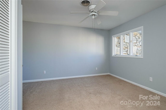 carpeted spare room featuring ceiling fan