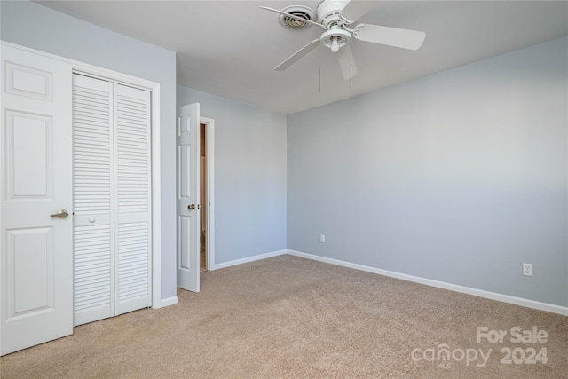 unfurnished bedroom with ceiling fan, light colored carpet, and a closet