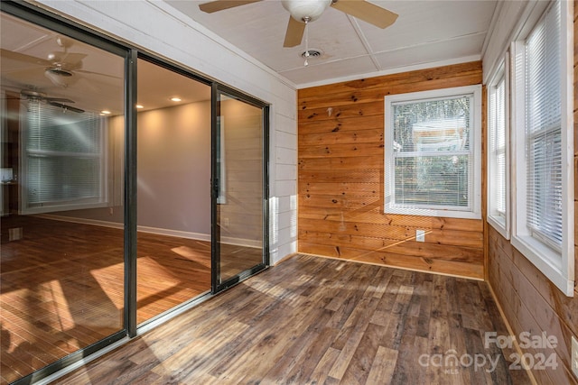 empty room featuring wood walls, hardwood / wood-style floors, and ceiling fan