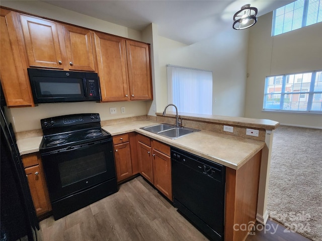 kitchen featuring kitchen peninsula, sink, black appliances, and light hardwood / wood-style floors