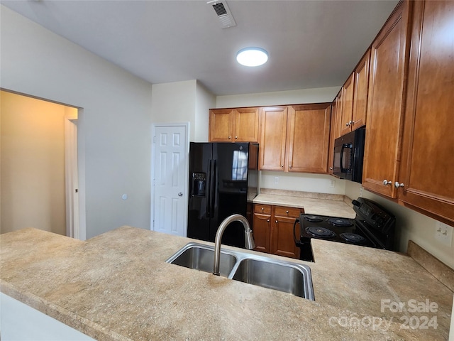 kitchen with black appliances, kitchen peninsula, and sink